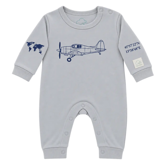 A light gray baby long-sleeve romper with a navy blue airplane graphic on the chest, a world map on one sleeve, and coordinates on the other sleeve, shown on a plain white background.